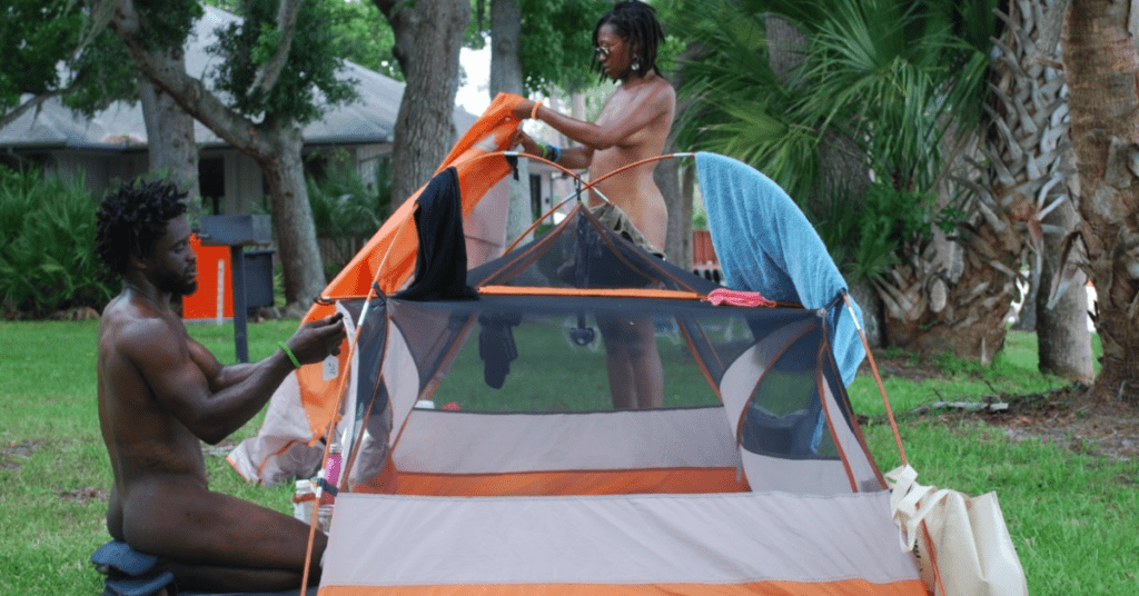 two nudists setting up a tent at cypress cove nudist resort